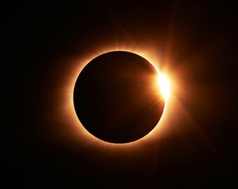 May include: A close-up of a total solar eclipse, showing the sun's corona as a bright ring around the moon's silhouette.