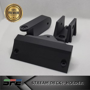 Può includere: Supporto nero per Stream Deck+, composto da più pezzi con finitura opaca. Il supporto include una base, una struttura di supporto e un componente incernierato. L'immagine include anche un sigillo dorato con la scritta "100% Premium Quality".