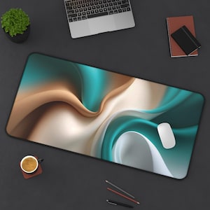 May include: A large rectangular mousepad with a black border features a flowing abstract design in shades of teal, brown, and white. A white computer mouse rests on the pad. A laptop, a small potted plant, and a cup of coffee are also visible.