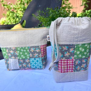 May include: A beige zippered pouch and a beige drawstring bag, both featuring a quilted top section and a lower section made of patchwork fabric squares in various floral, plaid, and geometric patterns in shades of green, pink, and blue.