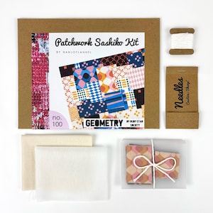Può includere: Un kit artigianale per patchwork sashiko. Include una scatola di cartone marrone con il testo "Patchwork Sashiko Kit" e "Geometry". Contiene tessuto, aghi, filo e un libretto con un colorato design patchwork. La parola "Needles" è stampata sul cartone.