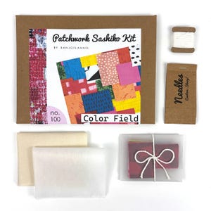 May include: A craft kit for patchwork sashiko, featuring a brown box with the text "Patchwork Sashiko Kit" and "Color Field." The kit includes fabric squares, needles, thread, and a booklet with colorful patchwork designs. The kit is labeled "no. 100."