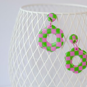 Könnte beinhalten: Ein Paar rosa und grüne karierte Ohrringe in Blumenform.