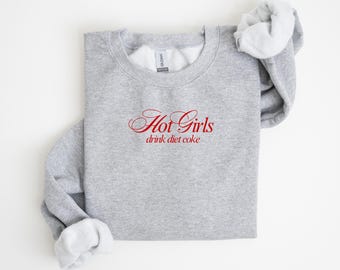Sudadera unisex con cuello redondo y bordado de Gildan con la frase "Chicas calientes beben Coca-Cola Light"