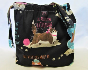 May include: Black drawstring bag with a cat print and the text "It's all about the cattitude" and "All visitors must be..."