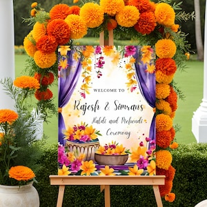May include: Welcome sign for a Haldi and Mehndi ceremony for Rajesh & Simran. The sign is decorated with purple curtains, yellow flowers, and a watercolor background. The sign is on an easel with marigold flower garlands.