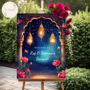 May include: A welcome sign for a Sangeet celebration with a blue background and a gold archway decorated with floral accents and lanterns. The text reads "Welcome to Raj & Simran's Sangeet".