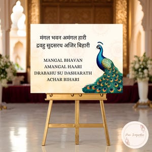 May include: A gold easel supports a cream-coloured sign featuring text and a peacock illustration. The peacock is rendered in shades of blue, green, and yellow. The sign includes text in English and another language.
