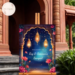 May include: A welcome sign for a Sangeet celebration with a blue background, gold lanterns, and pink flowers. The sign reads "Welcome to Raj & Simran's Sangeet".