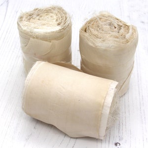 Rolls of undyed recycled sari silk ribbon with raw edges approx 75mm wide and 10m long