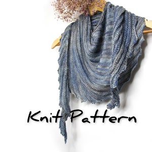 May include: A blue and grey knitted shawl with a scalloped edge, hanging on a wooden hanger. The text "Knit Pattern" is written below the shawl.