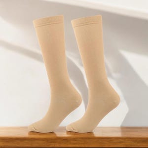 Può includere: Un paio di calze beige alte fino al ginocchio con una trama a coste.