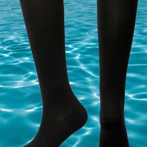 Può includere: Un paio di calze a compressione nere fino al ginocchio. Le calze sono realizzate in un materiale morbido e traspirante e sono progettate per aiutare a migliorare la circolazione e ridurre l'affaticamento delle gambe.