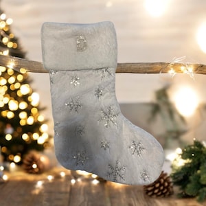 May include: White faux fur Christmas stocking with a silver snowflake pattern and a silver glitter letter "D" on the cuff.