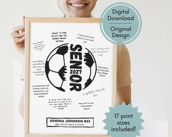 May include: A framed white poster featuring a black soccer ball graphic with the text SENIOR 2027 in the center. The design includes handwritten-style congratulatory messages from various people and a nameplate reading KENDRA JOHNSON #23 WATERLOO HIGH SCHOOL.