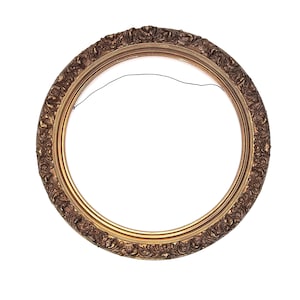 May include: A circular picture frame featuring a dark bronze finish with intricate, raised scrollwork and floral relief patterns along the outer edge. The inner rim is smooth and gold-toned, and a thin black hanging wire is attached to the back.