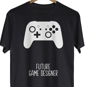 Op de afbeelding: Zwart T-shirt met een witte videogamecontroller-afbeelding en de tekst "FUTURE GAME DESIGNER".