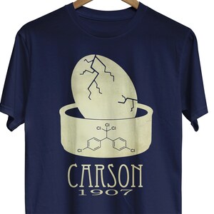 May include: A navy blue t-shirt with a white graphic of a cracked egg with a chemical formula inside. The text "CARSON 1907" is printed below the graphic.