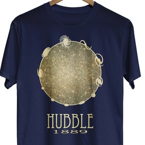 May include: Navy blue t-shirt with a gold glitter design of a galaxy with the text "HUBBLE 1889".