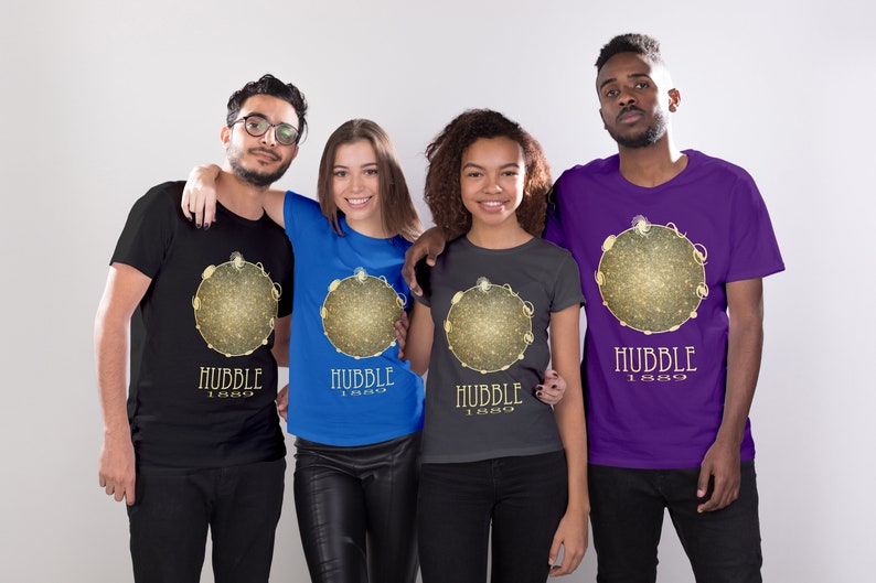 May include: Four people wearing t-shirts with a gold and black graphic of a galaxy with the text "Hubble 1990". The shirts are black, blue, gray, and purple.