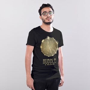 May include: A black t-shirt with a gold graphic of a galaxy with the text "HUBBLE 1889" underneath.