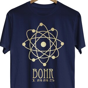 May include: A navy blue t-shirt with a gold atomic model and the text "BOHR 1885" printed on the front.