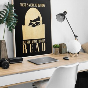 May include: A black and gold poster with the text "There is work to be done, but all I want to do is READ". A silhouette of a woman wearing glasses and reading a book is in the center of the poster.