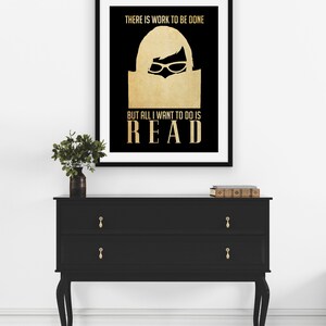 May include: A black and gold poster with the text "THERE IS WORK TO BE DONE BUT ALL I WANT TO DO IS READ". The poster features a silhouette of a person reading a book.