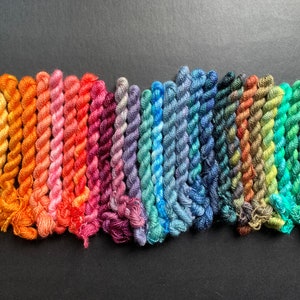 May include: A selection of colourful embroidery floss in a range of shades, from warm yellows and oranges to cool blues and greens. The floss is tightly wound, displaying a variety of colours for crafting and embroidery projects.