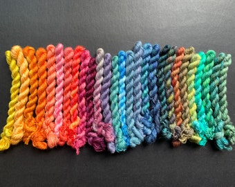 May include: A collection of colorful embroidery floss in a spectrum of hues, from warm yellows and oranges to cool blues and greens. The floss is tightly wound, showcasing a variety of shades for crafting and embroidery projects.
