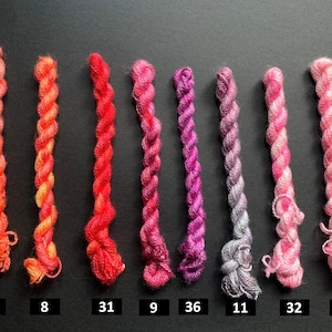 May include: A collection of eight twisted embroidery floss skeins in a gradient of colors from orange to pink. Each skein is labeled with a number, ranging from 6 to 36, against a dark background. Ideal for embroidery and craft projects.