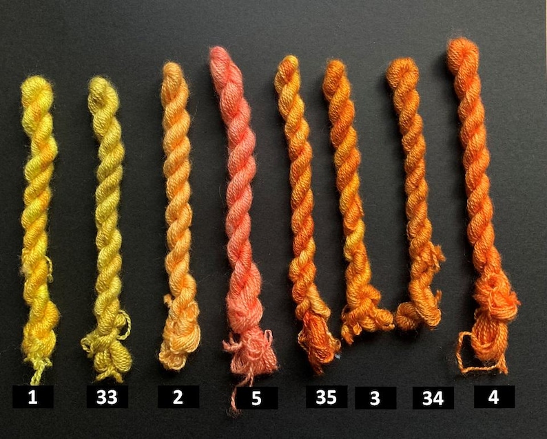 May include: A collection of eight twisted embroidery floss skeins in a gradient of yellow, orange, and coral hues. Each skein is labeled with a number from 1 to 35, showcasing a range of colors for crafting projects.