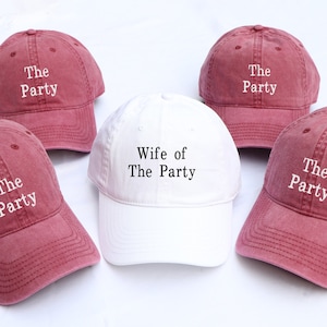 Könnte beinhalten: Fünf Baseballkappen, vier sind rotbraun und eine ist weiß. Die rotbraunen Kappen haben weißen Text mit der Aufschrift "The Party". Die weiße Kappe hat schwarzen Text mit der Aufschrift "Wife of The Party".