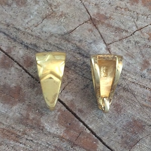 May include: Two gold-toned metal pendant bails with a star design on one side and a smooth surface on the other.
