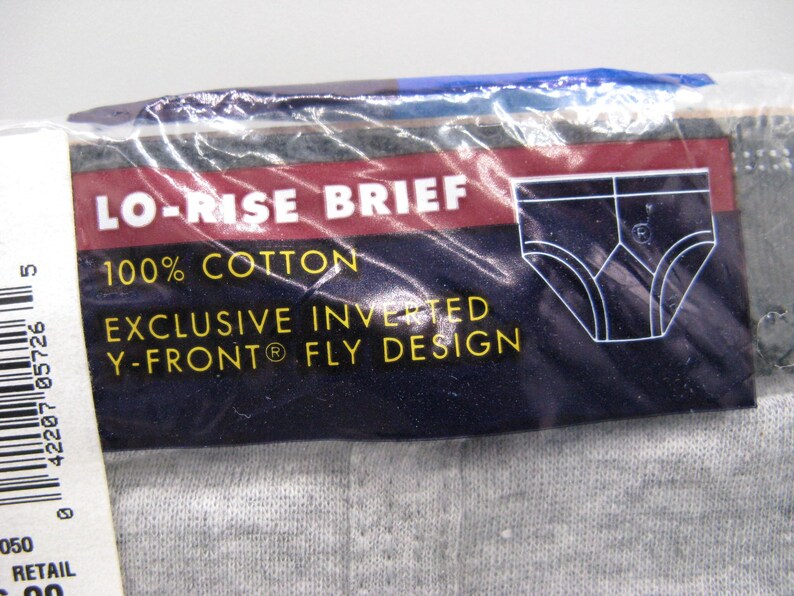 May include: A package of grey cotton lo-rise briefs featuring a dark blue label with white text that reads LO-RISE BRIEF, 100% COTTON, and EXCLUSIVE INVERTED Y-FRONT FLY DESIGN, accompanied by a white line drawing of the brief style.