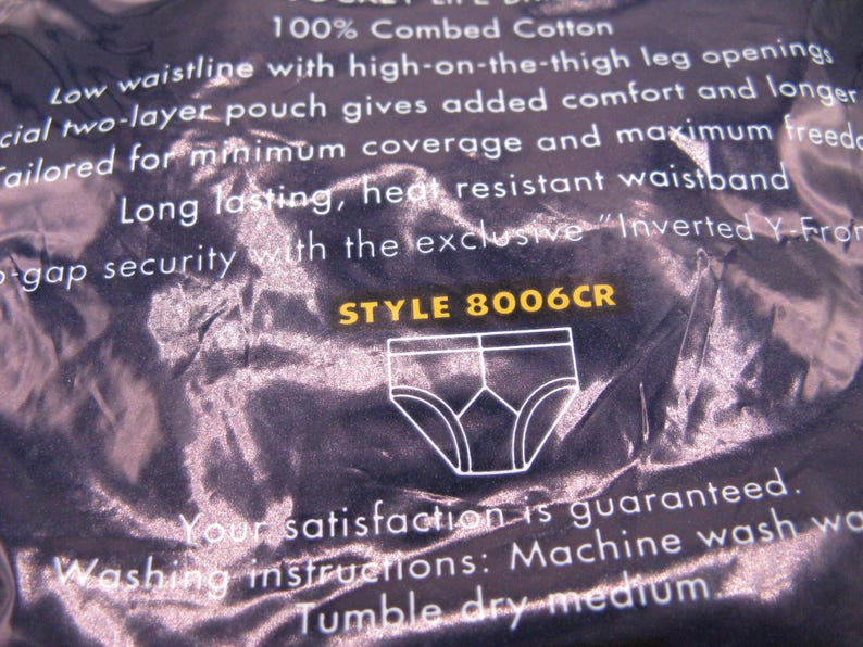 May include: A dark blue product package featuring white text describing 100% combed cotton underwear with a low waistline, high-on-the-thigh leg openings, and a two-layer pouch. The package displays the text STYLE 8006CR and a white line drawing of briefs.