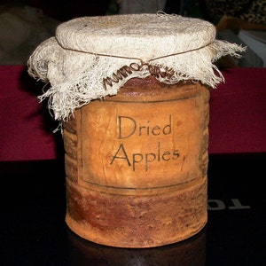 May include: A rustic brown jar with a white cloth lid and a label that reads "Dried Apples".