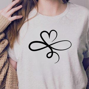 Pu&ograve; includere: Una maglietta bianca con un design a forma di infinito nero che incorpora una forma di cuore.