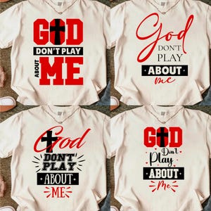 May include: Four cream-colored t-shirts with the phrase "God Don't Play About Me" in red and black lettering. Each shirt features a different design, including a cross graphic.