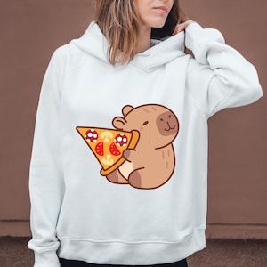 May include: White hoodie featuring a cartoon capybara holding a pizza slice. The pizza has red tomato slices, mushroom toppings, and a golden crust. The capybara is brown with a smiling face. The hoodie has a drawstring hood and long sleeves.