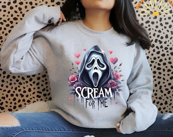 May include: A gray sweatshirt with a graphic print of the Ghostface character from the Scream movie franchise. The graphic includes a floral design and the text "Scream for Me".