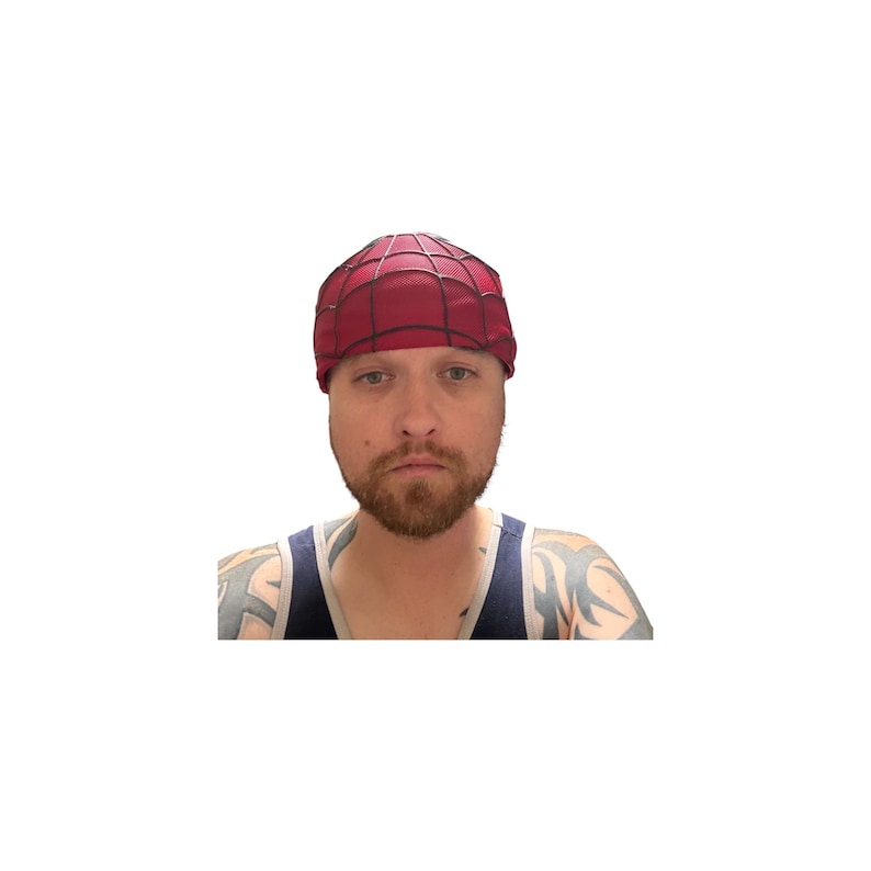 May include: A red and black Spider-Man themed cap. The cap features a web design and is worn on the head. The person in the image is wearing a blue tank top with tattoos on their arms.