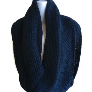 Op de afbeelding: Een donkerblauwe gebreide infinity sjaal. De sjaal is gemaakt van een zacht, comfortabel materiaal en is perfect om warm te blijven in de winter.