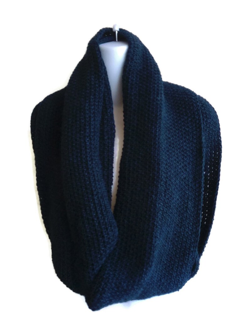 Op de afbeelding: Een donkerblauwe gebreide infinity sjaal. De sjaal is gemaakt van een zacht, comfortabel materiaal en is perfect om warm te blijven in de winter.