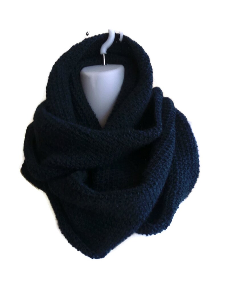 Op de afbeelding: Een donkerblauwe gebreide oneindige sjaal. De sjaal is gemaakt van een zacht, comfortabel materiaal en is perfect om warm te blijven in de winter.