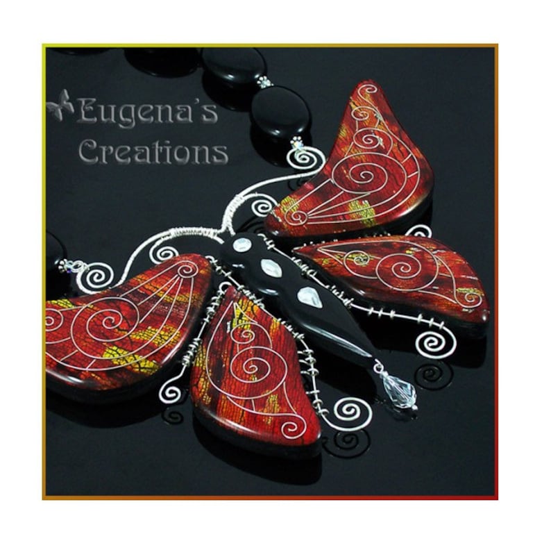 Picture of a butterfly necklace in Faux Cloisonne technique with a metal leaf inlay.