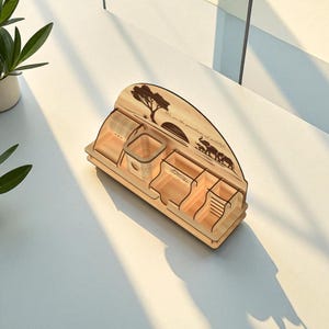 Puede incluir: Un organizador de escritorio de madera clara con m&uacute;ltiples compartimentos. Presenta un dise&ntilde;o cortado con l&aacute;ser de un &aacute;rbol, elefantes y el texto "We are the guardians of wildlife". Dise&ntilde;ado para guardar bol&iacute;grafos, l&aacute;pices y otros &uacute;tiles de oficina.
