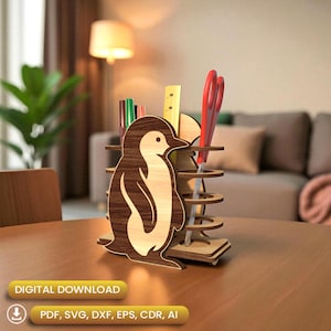 Puede incluir: Un organizador de escritorio de madera con forma de pingüino, con un cuerpo de madera clara y detalles en marrón oscuro. Contiene bolígrafos, una regla y tijeras rojas. La base tiene agujeros circulares para almacenamiento adicional. Se muestran las palabras "DESCARGA DIGITAL" y opciones de tipo de archivo.