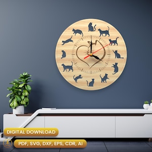 Op de afbeelding: Een ronde houten klok met een lichte houtnerf. De wijzerplaat heeft zwarte katten silhouetten en een hartvormig ontwerp. De wijzers zijn zwart en rood. De klok is aan een blauwe muur bevestigd. Diameter ongeveer 30 cm.