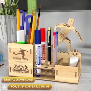 May include: A wooden desk organiser with a football theme. The organiser has a compartment for pens, pencils, and markers, as well as a small drawer for other items. The organiser is decorated with a football, a football player, and the word "FOOTBALL".